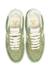 Baskets en daim vert avec une texture shaggy et des accents crème, dotées de lacets blancs et d'un logo doré sur une languette rembourrée.