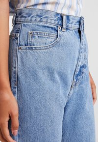 Ljusblå högmidjade denimjeans med en något lös passform, femficksdesign och synliga sömmdetaljer. Slät textur.