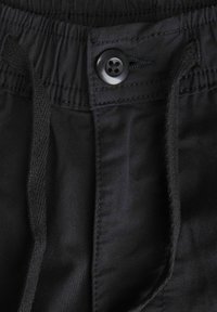 Pantalones cortos negros con una cinturilla elástica ajustable, que cuentan con un cierre de botón, fabricados en una tela suave con una superficie texturizada y detalles de costura.