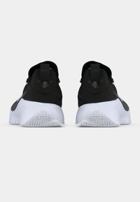 Μαύρα αθλητικά παπούτσια με υφή στο πάνω μέρος, στρογγυλή φτέρνα και λευκές καουτσούκ σόλες με σχέδιο στο πέλμα και λουράκια για εύκολη εφαρμογή.