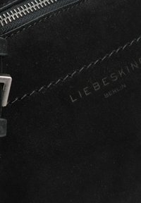 Borsa a tracolla in suede nero con zip argentata, dotata di una tracolla piatta e nome del marchio in rilievo "LIEBESKIND BERLIN" sul lato. Texture liscia.