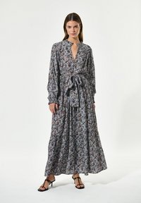 Lange bloemenjurk met een diepe V-hals, een ceinture taille, volumineuze mouwen en een vloeiende rok in tinten blauw, paars en wit.