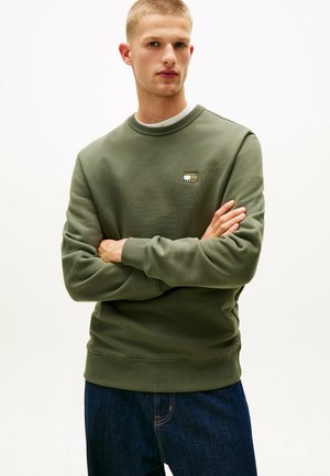 Grøn sweatshirt lavet af tekstureret stof med rund halsudskæring og ribbede manchetter. Har et lille logo patch på brystet.