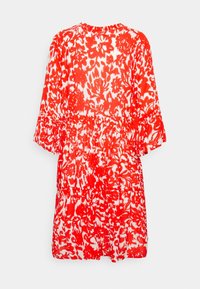 Robe à motifs floraux rouges et blancs, manches courtes, taille froncée et encolure ronde. Tissu léger à la texture douce.