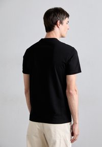 T-shirt de algodão preto com um corte clássico de gola redonda, mangas curtas e um ajuste descontraído. O tecido parece suave, com um acabamento liso e sem padrões visíveis.