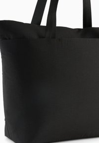 Sac fourre-tout noir en tissu avec deux poignées solides, de forme rectangulaire et une texture lisse sans motifs ni détails matériels visibles.