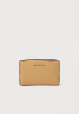 Portefeuille compact en cuir fauve avec le logo argenté Michael Kors centré sur le devant, placé sur un fond clair uni.