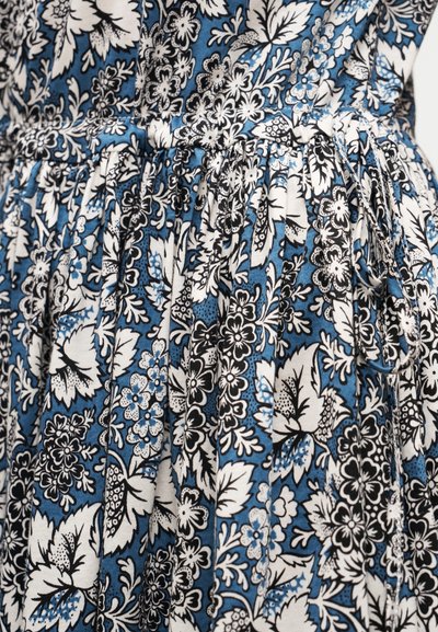 Tissu bleu avec des motifs floraux et de feuilles denses en blanc et noir, doté de plis froncés et d'un détail de nœud noué à la taille.