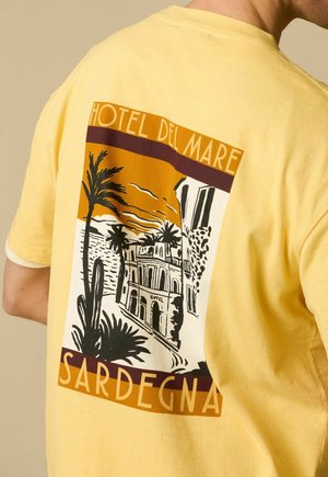 Gelbes T-Shirt mit einem illustrierten Design eines Küstenhotels, Palmen und Gebäuden, mit der Aufschrift "Hotel Del Mare" und "Sardegna".