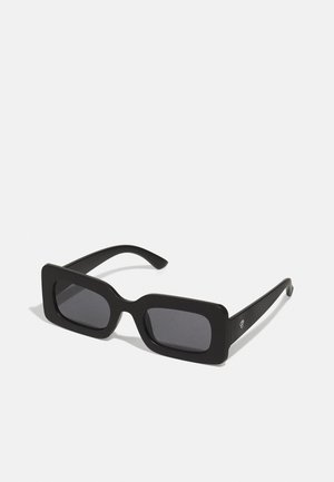 Zwarte zonnebril met een opvallend vierkant montuur, donkere getinte lenzen en een matte afwerking. Bevat een licht gebogen neusstuk en slanke pootjes.