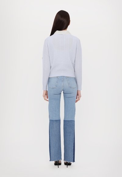 Maglione a maglia leggera blu chiaro con un colletto a contrasto, abbinato a pantaloni flare in denim blu chiaro a vita alta con un pannello blu scuro.