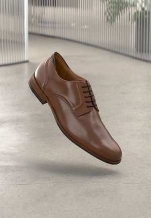 Chaussure habillée en cuir marron avec une finition lisse, bout arrondi et lacets noirs, dotée d'une semelle contrastante de couleur brun clair.