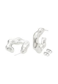 Abstracte zilveren hangers in de vorm van een ovale ring, met een golvend ontwerp, glanzende oppervlakken en twee verwisselbare accentringen.