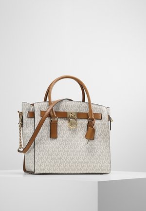 Beige en bruine designertas met monogrampatroon, dubbele handvatten, afneembare schouderriem en goudkleurige logohanger aan de voorkant.