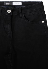 Vaqueros de mezclilla negra con un diseño clásico de cinco bolsillos, cierre frontal con botón y un sutil detalle de costura. La etiqueta dice "CECIL DENIM."