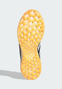 Sole sportovní obuvi s vzorem včelího plástu v oranžové a bílé barvě, se strukturovanými úchyty a černými postranními akcenty.