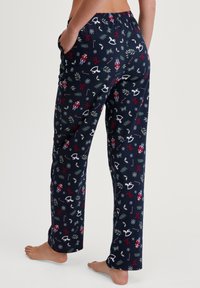 Marineblauwe pyjamabroeken met feestelijke patronen, waaronder sneeuwvlokken, notenkrakers en vakantiethema's. Gemaakt van zachte, comfortabele stof met zakken.