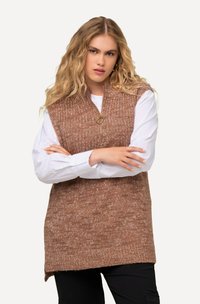 Gilet lavorato a maglia in toni di marrone, con colletto alto e chiusura a mezza zip. Indossato sopra una camicia bianca, con un aspetto testurizzato e accogliente.