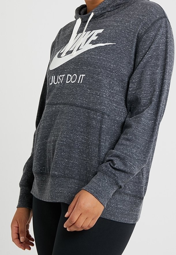Mörkgrå hoodie i mjukt, texturerat tyg med en kenguruficka, dragsko huva och vit Nike-logga. "Just Do It" tryckt på framsidan.