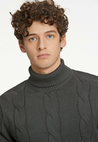 Maglione grigio a collo alto in maglia grossa con scollatura a costine. Presenta un motivo testurizzato e un materiale morbido, adatto per il clima fresco.