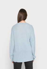 Sweater de malha azul claro com um corte largo, mangas largas e decote redondo. Tecido texturizado com um padrão de trama subtil.