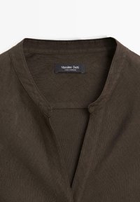 Chemise en lin marron foncé avec col officier et encolure fendue, portant une étiquette "Massimo Dutti Made in Morocco" à l'intérieur du col.