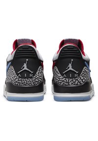 Baskets noires et grises avec un talon texturé, des accents rouges et bleus, une tige en mesh et une semelle en caoutchouc avec une unité Air visible.