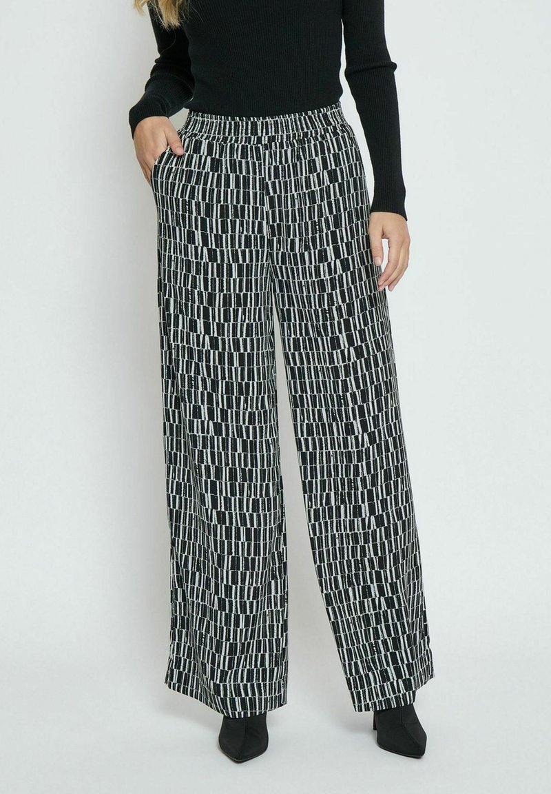 Wide-leg pants in a black and white geometric pattern, featuring an elastic waistband, side pockets, and a lightweight fabric.