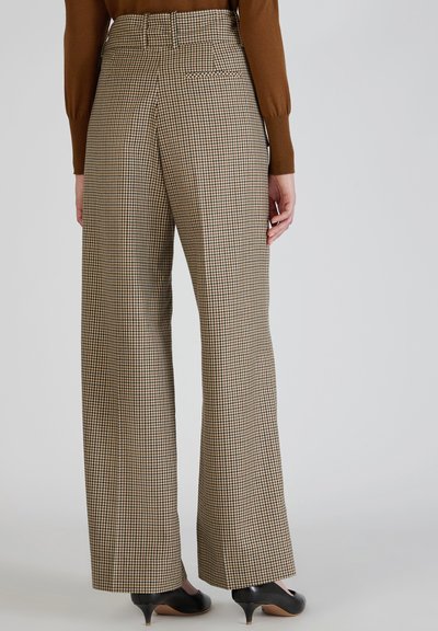 Bruine geruite hoge taillebroek met wijd uitlopende benen en twee achterzakken, gecombineerd met zwarte hakken. De textuur lijkt soepel en gestructureerd.