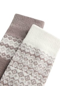 Dve vlnené ponožky, jedna svetlohnedá a jedna krémová, obe s prepracovanými bielymi a hnedými geometrickými vzormi pri manžetách.