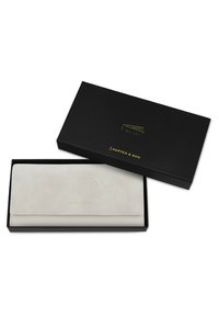 Lichtbeige portemonnee in een zwarte doos, met een gladde textuur, gouden details en een minimalistisch ontwerp met een omslagklep.