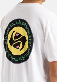 Camiseta de algodón blanca que presenta un gráfico circular en la parte posterior con un fondo amarillo, diseño negro y acentos coloridos.