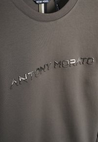 Felpa grigia con colletto rotondo e logo nero lucido "ANTONY MORATO" sul petto, realizzata in tessuto morbido e liscio.