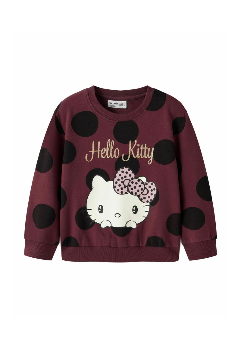 Sudadera color marrón con grandes lunares negros, que presenta un gráfico de Hello Kitty en blanco con un lazo de lunares rosas y texto dorado.