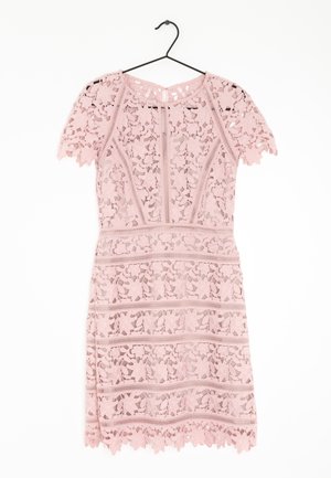 Růžové krajkové šaty s květinovými vzory, krátkými rukávy a vroubkovaným lemem, zavěšené na černém ramínku na bílém pozadí.