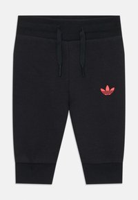Melni kokvilnas šortai ar elastīgu vidukli un aukliņām. Uz kreisā augšstilba ir sarkanais Adidas trīszaru logos.