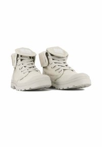 Stivali mid-top in canvas beige con allacciatura frontale, suola in gomma e linguetta pieghevole. Presentano una patch con logo sulla linguetta e accenti testurizzati.