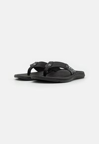 Tongs noires avec des semelles en caoutchouc texturé et des brides en tissu avec un accent à motifs. Le design est plat et ouvert à l'avant.