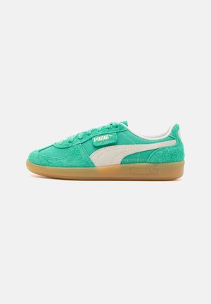 Sneaker verde in suede con dettagli in rete, logo bianco e suola in gomma. Presenta una tomaia testurizzata e chiusura con lacci. Design a profilo basso.