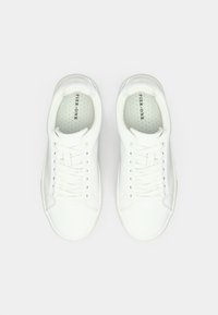 Λευκά αθλητικά παπούτσια με λευκό κορδόνι και λεία υφή, στρογγυλή μύτη, τρυπητές σόλες, και διακριτική επωνυμία στη γλώσσα. Μινιμαλιστικός σχεδιασμός.