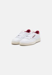 Weiße Ledersneaker mit burgunderfarbenen Akzenten, runder Zehenform und dicker Gummisohle. Ausgestattet mit Schnürdesign und angebrachter Markenlabel an der Seite.