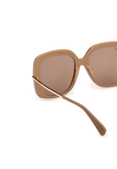 Lunettes de soleil carrées surdimensionnées marron avec des verres dégradés et des branches en métal doré sur fond blanc.