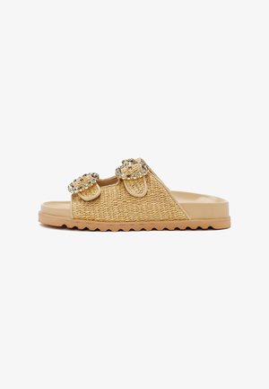 Sandalia de slide beige con textura tejida, dos correas ajustables con hebillas circulares adornadas con brillantes transparentes.