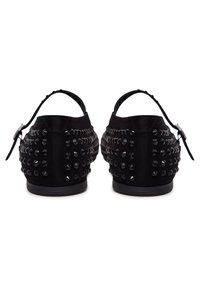 Czarne buty zamszowe z elastycznymi paskami, ozdobione dużymi czarnymi ćwiekami po bokach, z zaokrąglonym noskiem i płaską podeszwą.