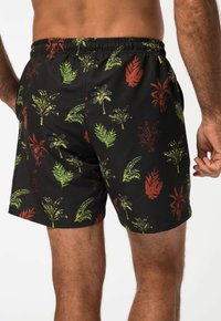 Shorts de bain noirs avec des motifs colorés de feuilles de palmier et de plantes, taille élastique et fentes latérales pour le confort et la mobilité.