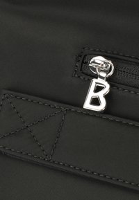 Borsa nera in tessuto con una tasca con zip. Zip argentata con un ciondolo a forma di "B", dettaglio di cucitura e superficie liscia.