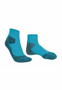 Un par de calcetines deportivos de longitud hasta el tobillo en azul brillante con acolchado texturizado negro en las zonas del talón, los dedos y la suela.