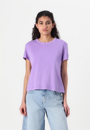Kortermet, avslappet T-skjorte i lavendel i myk stoff med rund hals, kombinert med lyse høytaljede jeans.