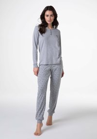 Pigiama grigio a maniche lunghe con colletto abbottonato, pantaloni grigi a fantasie con stelle navy, tessuto morbido e polsini aderenti alle caviglie.