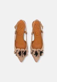 Chaussures slingback en cuir beige avec un bout pointu, des embellissements floraux en noir et beige, et une semelle intérieure tan avec un logo en relief.